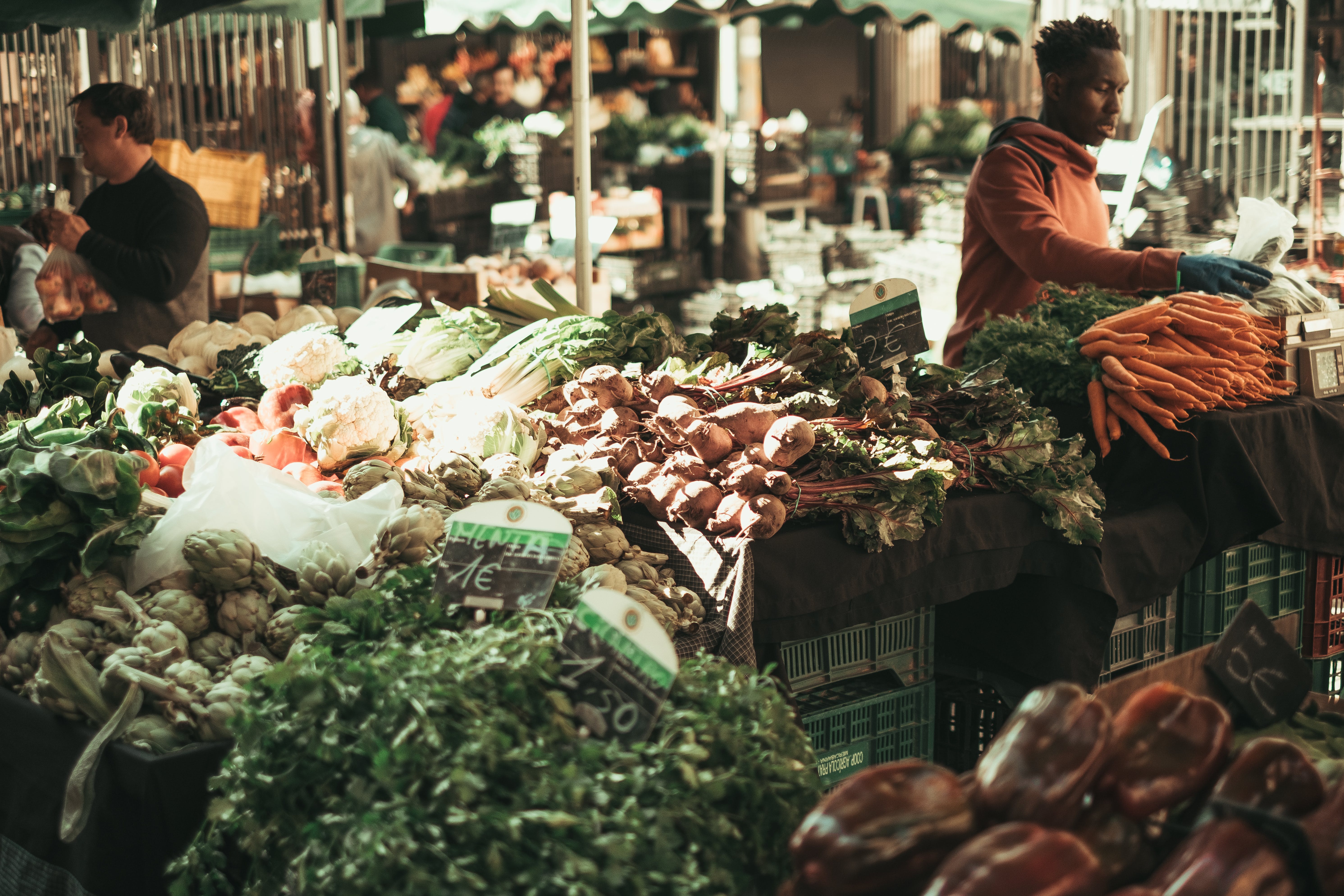 A group of people at a well-lit vegetable market in the evening.