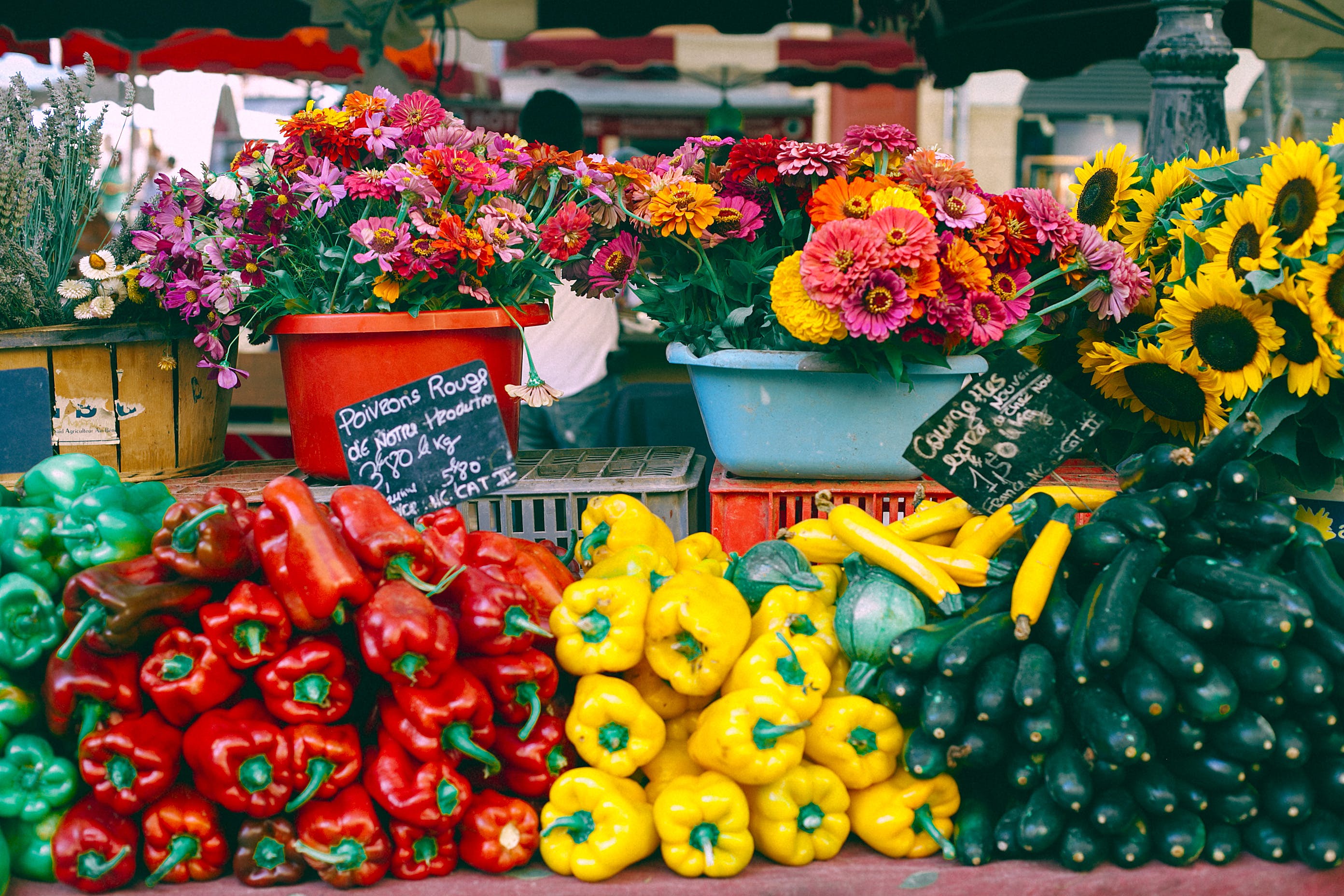 Bell peppers, zucchini, and flowers being sold at the farmer's market.